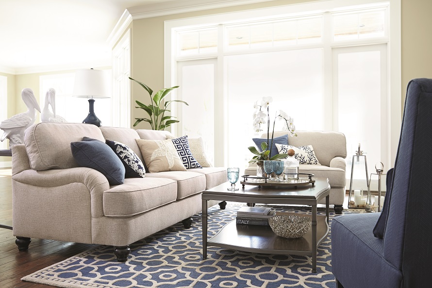 Sofa, oversized chair and armless chair with a coffee table on a patterned blue rug.