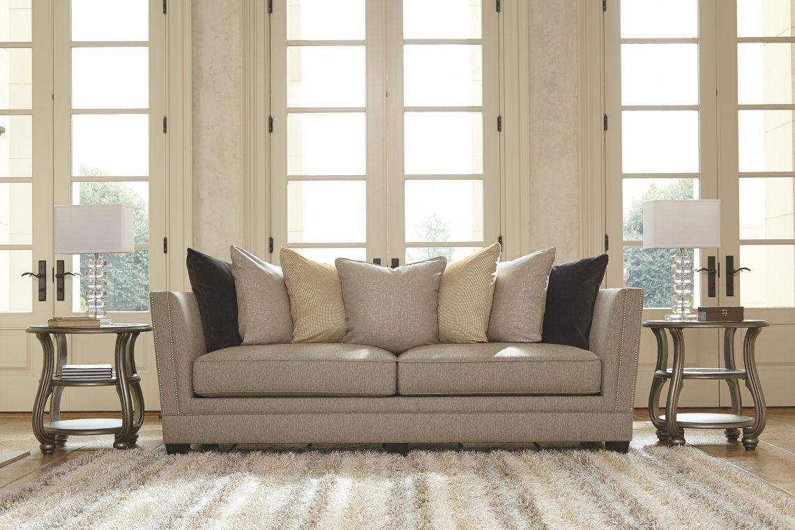 奶油色的沙发，上面有几层柔和的枕头，前面有一条毛茸茸的条纹地毯。